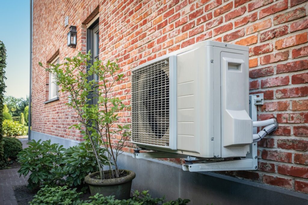 Op de foto zie je een buitenunit van een klimaatbeheersingssysteem keurig gemonteerd tegen een bakstenen gevel. Dit valt onder de installatie- en onderhoudsdienst voor warmtepompen of airconditioners. Het hoofddoel is het bieden van comfortabele verwarming en koeling in huis met zo min mogelijk energieverspilling. De unit rust op een stevige, roestvrije muurbeugel die trillingen dempt en de gevel beschermt. Dankzij het compacte formaat past hij ook bij woningen met beperkte buitenruimte en zorgt de weerbestendige behuizing voor langdurige bescherming tegen vocht en corrosie. Bovendien is het ventilatorenrooster zo ontworpen dat de unit fluisterstil draait, zodat je geen hinder hebt van geluid tijdens warme dagen.